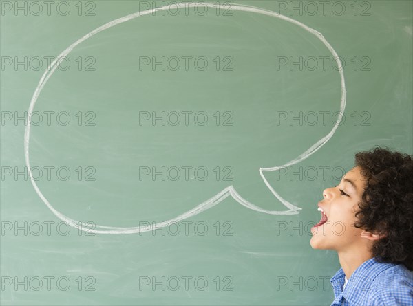 Mixed race boy shouting into speech bubble on chalkboard