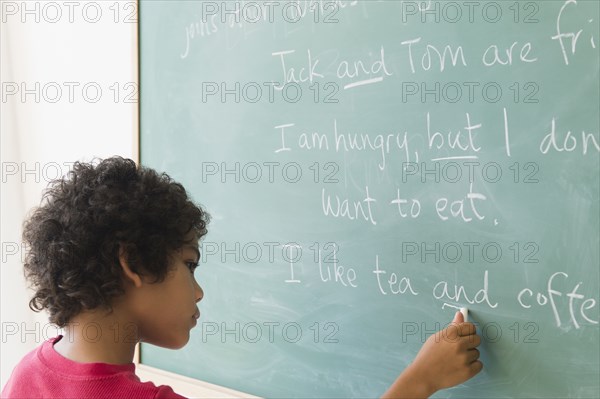 Mixed race boy writing on chalkboard in grammar lesson