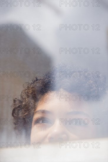 Mixed race boy looking out window