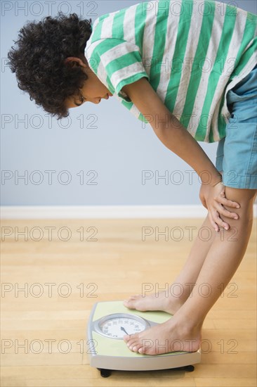 Mixed race boy weighing himself on scale