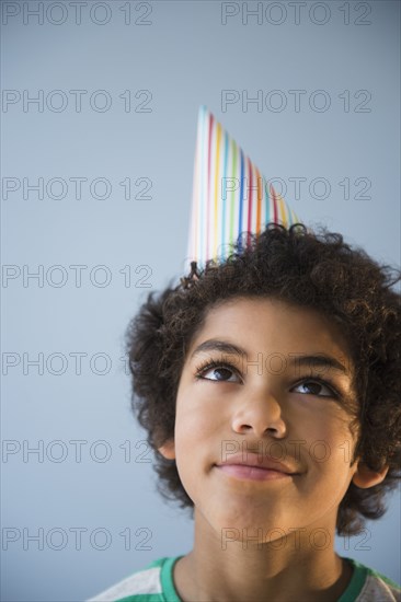Mixed race boy wearing party hat