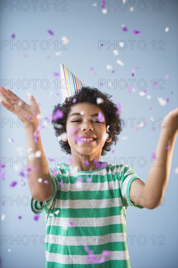 Mixed race boy throwing confetti at party