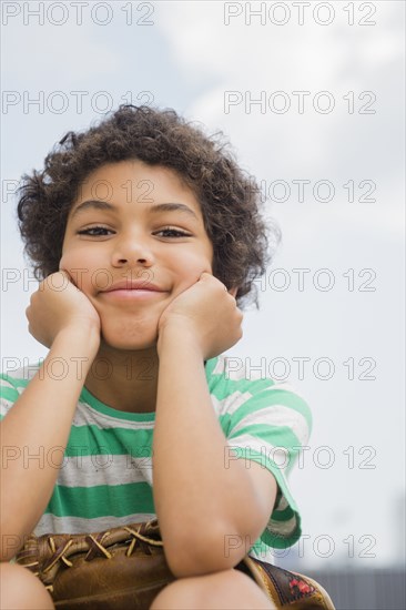 Mixed race boy holding baseball glove outdoors