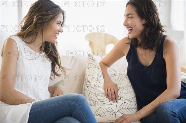 Hispanic women talking on sofa