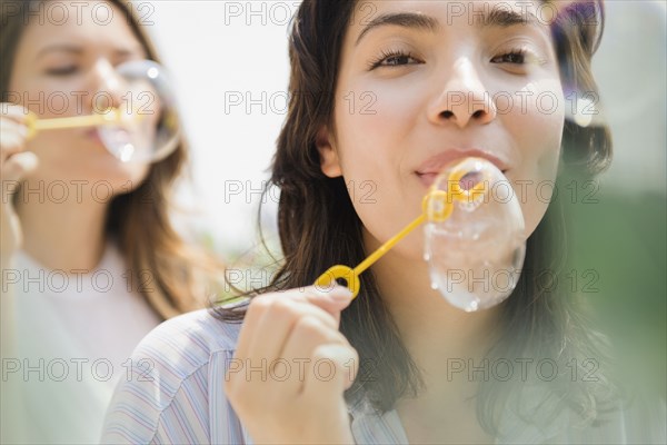 Hispanic women blowing bubbles outdoors