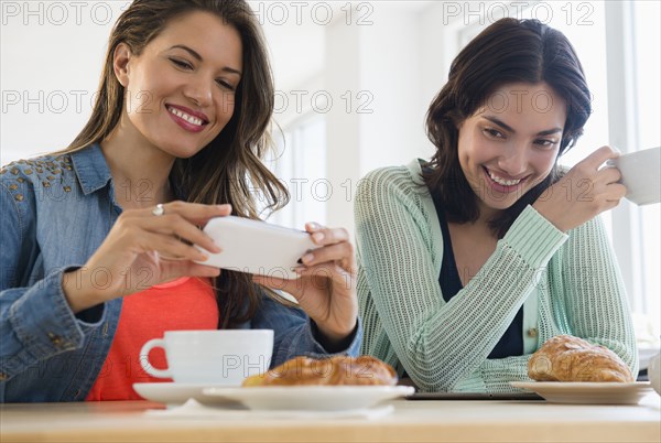 Hispanic women taking cell phone photograph of breakfast