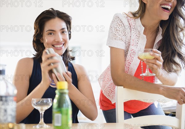 Hispanic women mixing cocktails at party