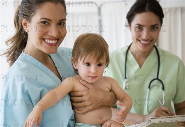 Pediatrician doctor and nurse holding baby girl in hospital