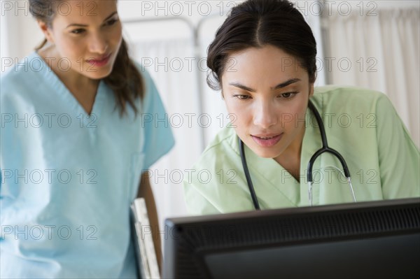 Hispanic nurses working together on computer at hospital