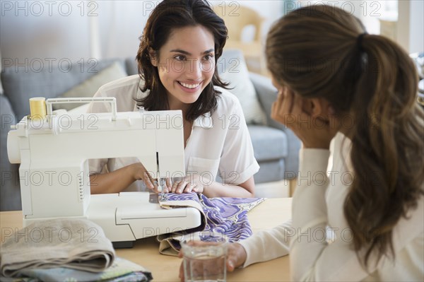 Hispanic women using sewing machine in living room