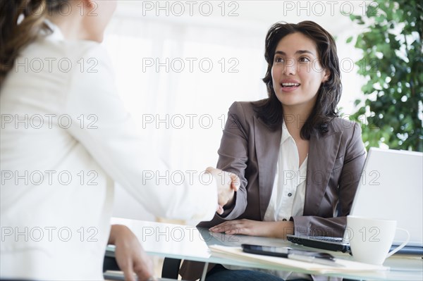 Hispanic businesswomen shaking hands in office