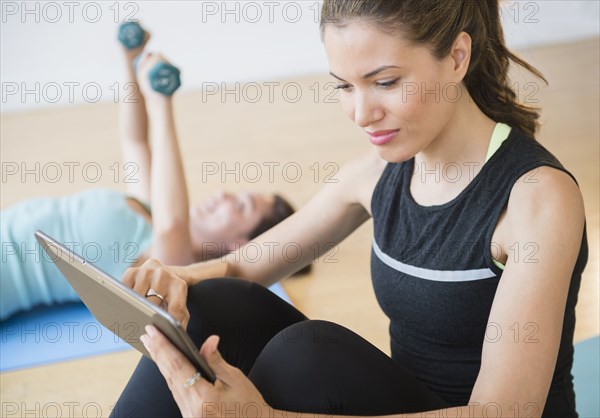 Hispanic woman using digital tablet in yoga studio