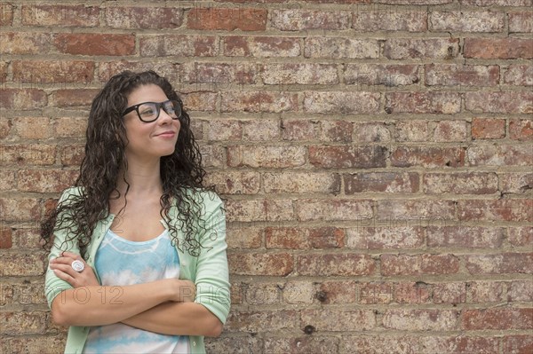 Pensive mixed race woman standing with arms crossed