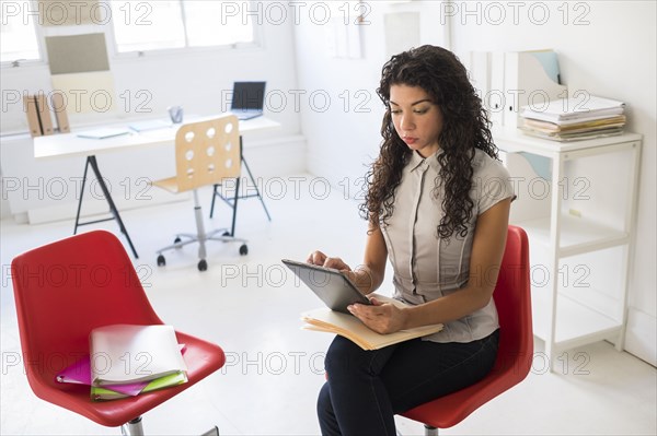 Mixed race businesswoman using digital tablet in office