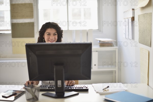 Mixed race businesswoman working on computer at desk in office