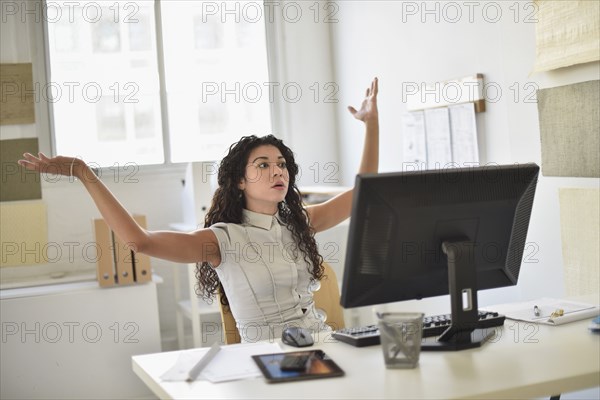 Mixed race businesswoman frustrated at computer at desk in office