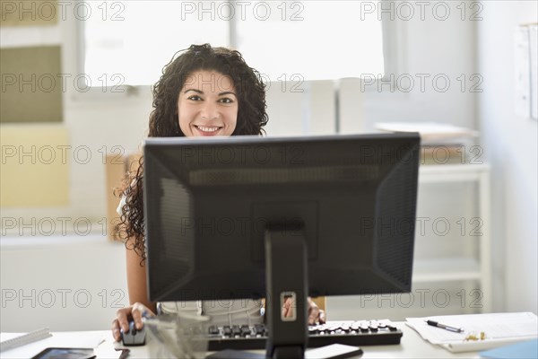 Mixed race businesswoman working on computer at desk in office