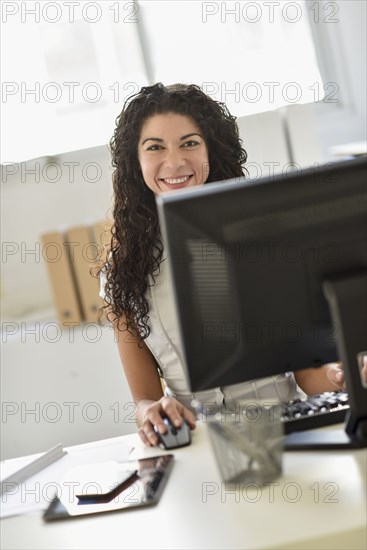 Mixed race businesswoman working on computer at desk in office