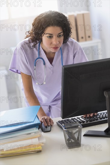 Mixed race nurse using computer in office