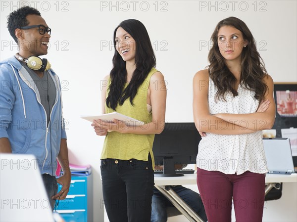 Annoyed businesswoman ignoring colleagues in office