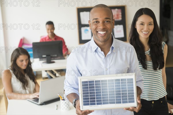 Businessman holding solar panel model in office