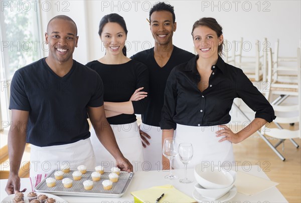 Caterers smiling with food in event space