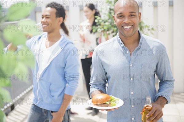 Man having beer and burger at backyard barbecue