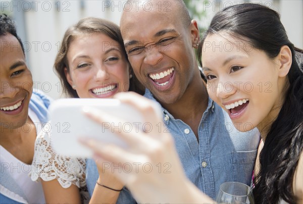 Friends taking cell phone photograph at party