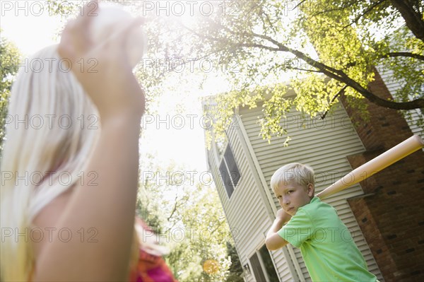 Caucasian children playing baseball in backyard