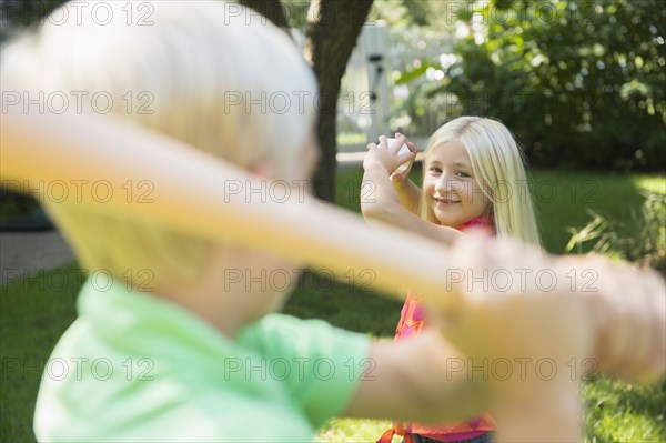 Caucasian children playing baseball in backyard