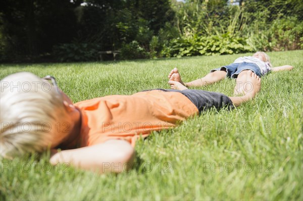 Caucasian children laying on lawn in backyard