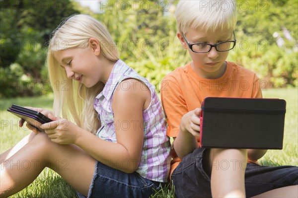 Caucasian children using digital tablets in backyard
