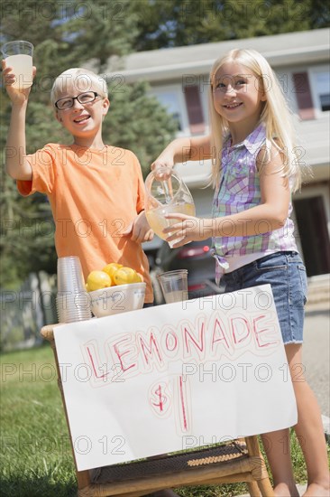 Caucasian children selling lemonade in front yard