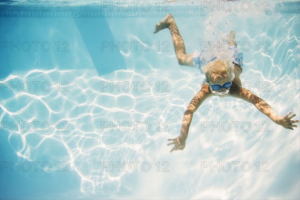 Caucasian boy swimming underwater in pool