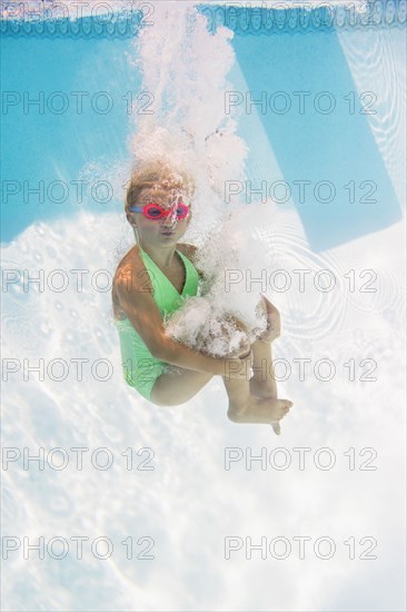 Caucasian girl swimming underwater in pool