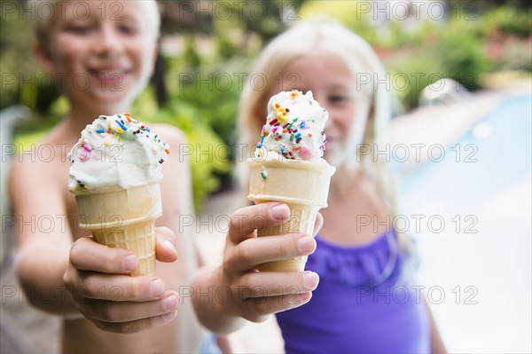 Caucasian children eating ice cream near swimming pool