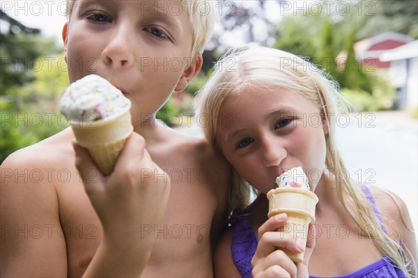 Caucasian children eating ice cream near swimming pool