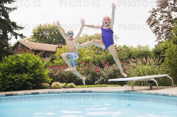 Caucasian children jumping into swimming pool