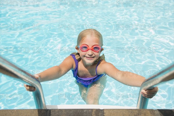 Caucasian girl climbing out of swimming pool