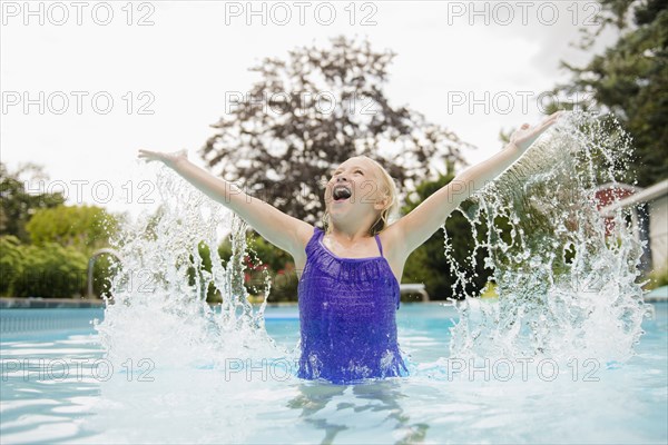 Caucasian girl splashing in swimming pool