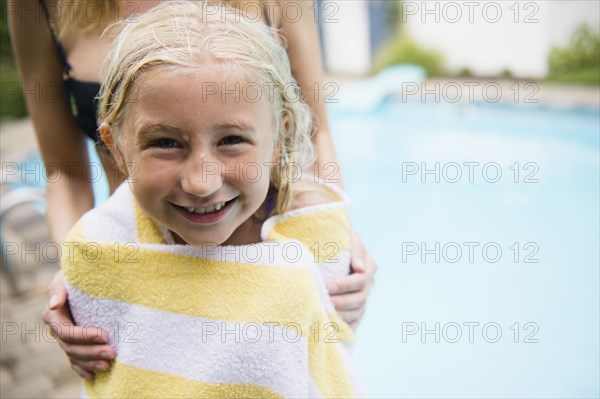 Caucasian mother drying daughter near swimming pool