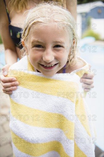 Caucasian mother drying daughter near swimming pool