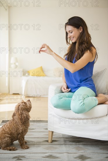 Caucasian woman training pet dog in living room