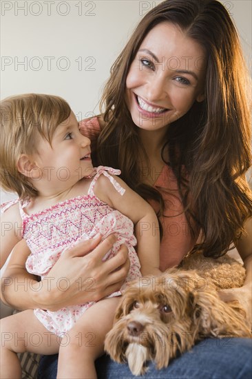 Caucasian woman holding daughter and pet dog