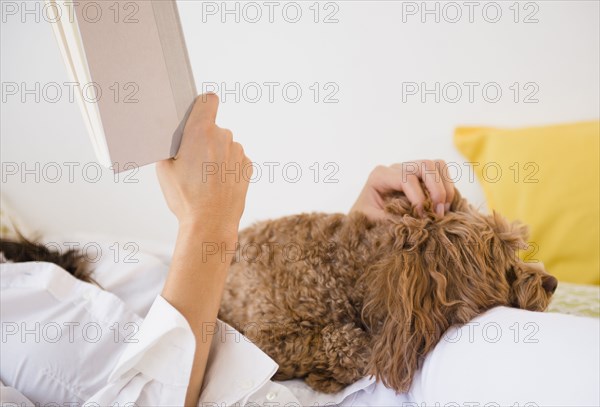 Caucasian woman reading with pet dog