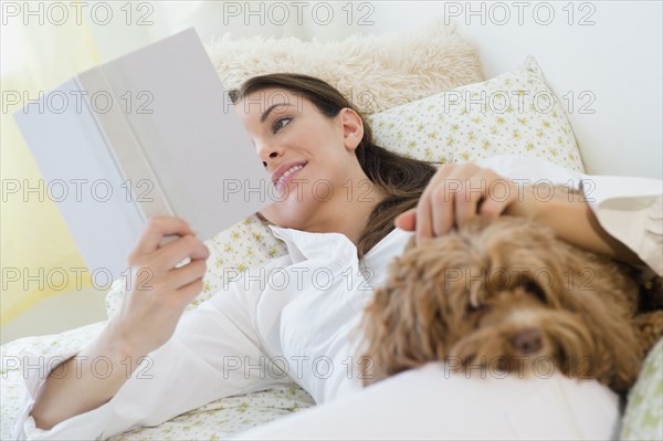 Caucasian woman reading with pet dog