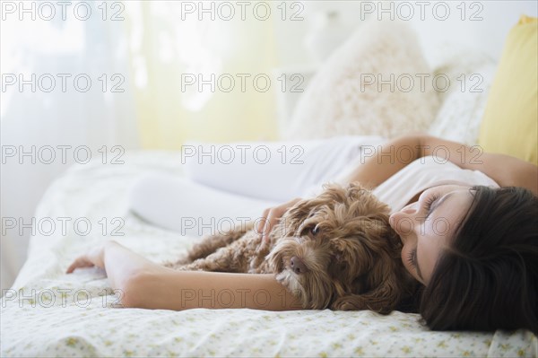 Caucasian woman hugging pet dog in bed