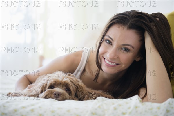 Caucasian woman hugging pet dog in bed