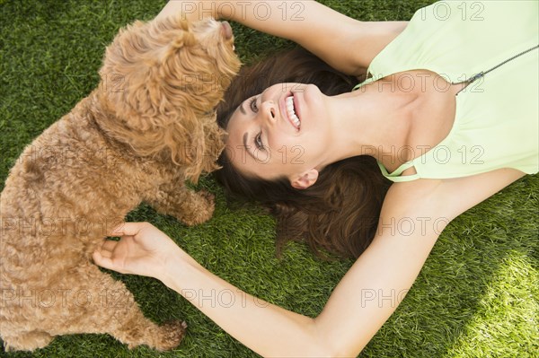 Caucasian woman playing with dog on lawn