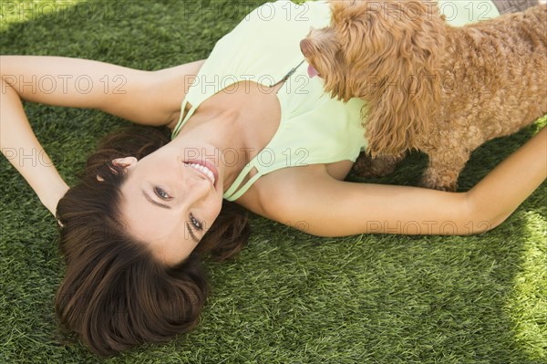 Caucasian woman playing with dog on lawn